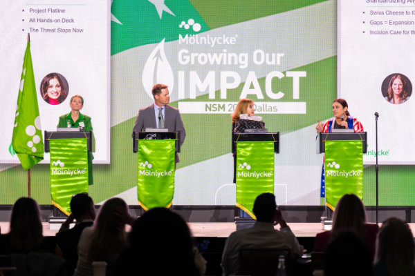 Molnlycke Growing Our Impact NSM four presenters on stage each standing behind a podium.